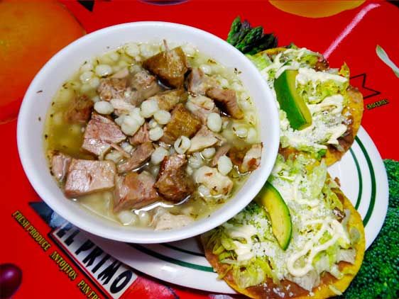 A bowl of pozole with tostadas